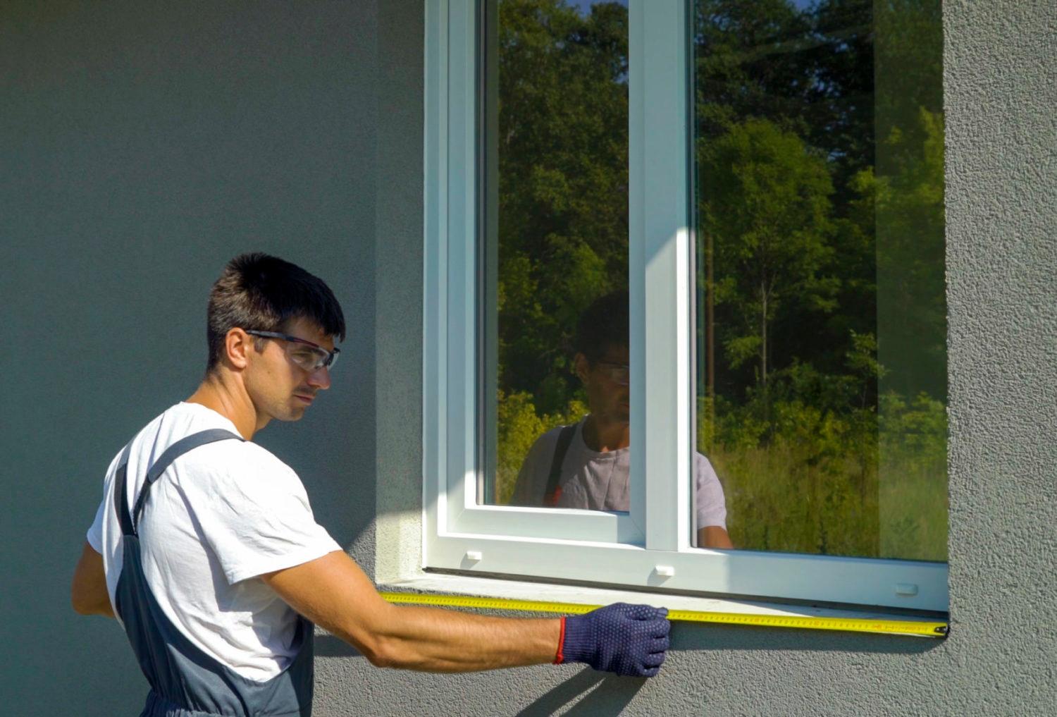 Man worker in safety glasses cleaning surface for PVC window metal sill installation