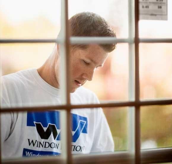 Man in white shirt with Window Nation logo installing a window