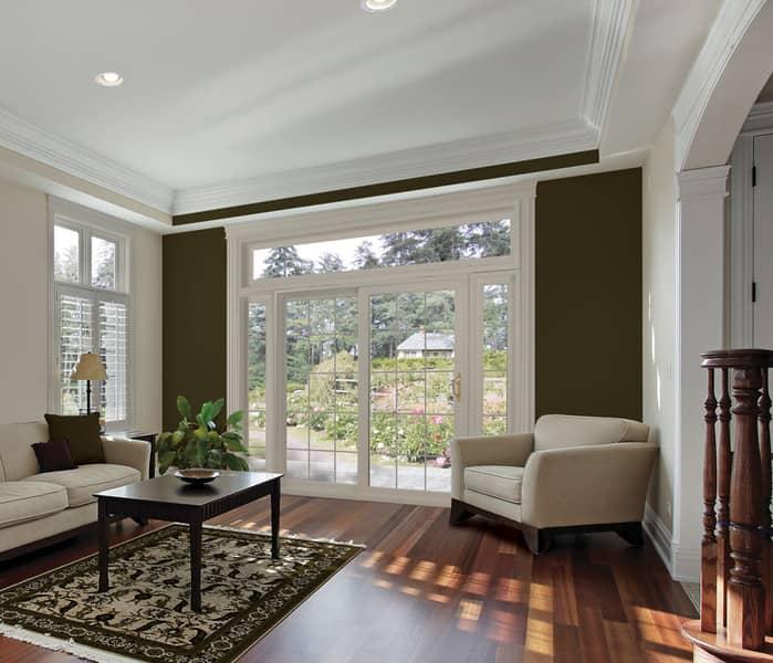 Living room with white french doors, a white couch and chair, wood floors, and a coffee table on a rug.